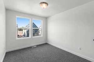 Empty room featuring baseboards and dark colored carpet