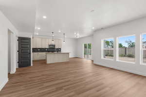 Kitchen with open floor plan, decorative backsplash, recessed lighting, an island with sink, and light wood-style floors