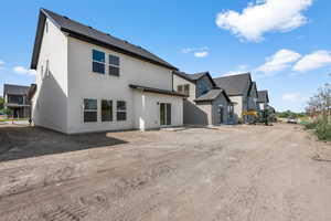 Rear view of house featuring stucco siding, a residential view, and roof with shingles