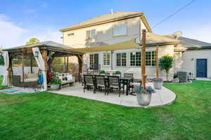 Back of house with a gazebo, outdoor lounge area, a patio, a lawn, and stucco siding