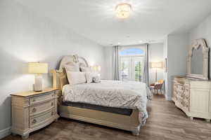 Bedroom with dark wood-style flooring, access to outside, and recessed lighting