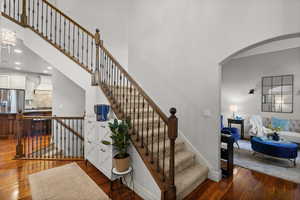 Staircase featuring hardwood / wood-style floors, arched walkways, recessed lighting, and a high ceiling