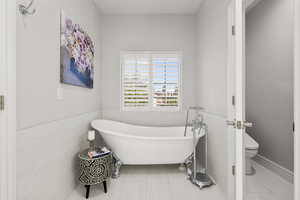 Bathroom with a freestanding bath, tile walls, a wainscoted wall, and tile patterned flooring