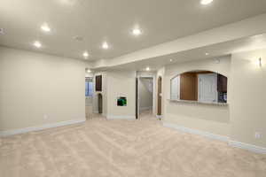 Empty room with light colored carpet, arched walkways, recessed lighting, and a textured ceiling
