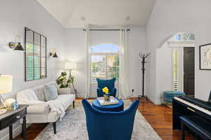 Sitting room with wood finished floors, healthy amount of natural light, arched walkways, and high vaulted ceiling