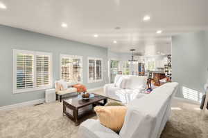 Living area featuring light carpet, recessed lighting, and a chandelier