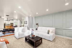 Living area with a decorative wall, recessed lighting, light colored carpet, and arched walkways
