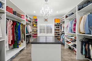 Walk in closet with a chandelier and wood finished floors