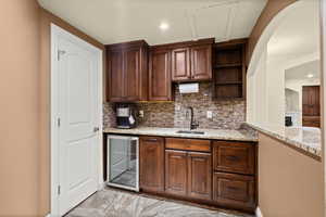 Kitchen featuring wine cooler, decorative backsplash, recessed lighting, open shelves, and light stone counters