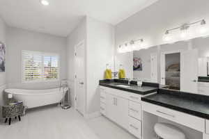Full bath featuring ensuite bathroom, a soaking tub, vanity, and tile patterned floors
