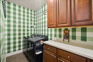 Laundry area with wallpapered walls, cabinet space, and tile patterned flooring