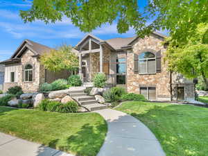 Craftsman-style house featuring a front yard, stone siding, and brick siding