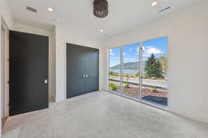 Unfurnished bedroom with a water and mountain view, recessed lighting, a closet, and carpet