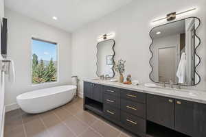 Full bath with double vanity, a freestanding tub, light tile patterned floors, and recessed lighting