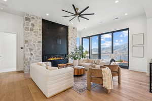 Living room featuring a mountain view, a stone fireplace, ceiling fan, light wood-style floors, and recessed lighting