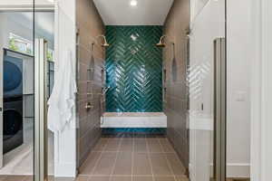 Full bath featuring a stall shower, estacked washer and dryer, and tile patterned flooring