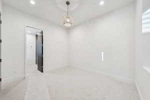 Empty room with recessed lighting, light carpet, and a chandelier