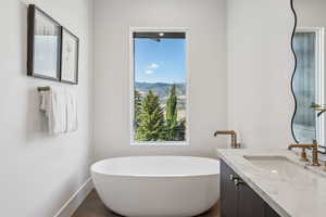 Full bathroom with vanity, a freestanding tub, dark tile patterned flooring, and a mountain view