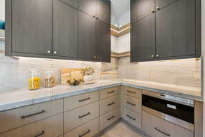 Kitchen with tasteful backsplash, modern cabinets, open shelves, and light stone counters