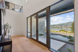 Doorway featuring a water and mountain view, wood finished floors, a high ceiling, and french doors