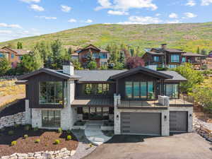 Contemporary home featuring a chimney, stone siding, and driveway