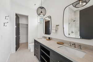 Bathroom featuring light tile patterned flooring, double vanity, and tiled shower