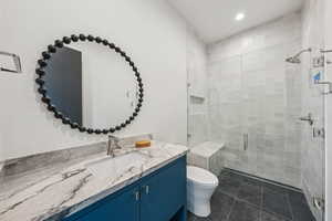 Full bathroom featuring vanity, a shower stall, dark tile patterned floors, and recessed lighting