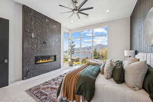 Carpeted bedroom featuring a water and mountain view, a fireplace, a ceiling fan, and recessed lighting