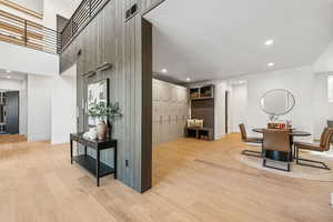 Dining space featuring recessed lighting, light wood-style floors, wood walls, and a high ceiling