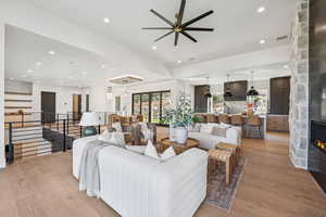 Living room with recessed lighting, light wood finished floors, a fireplace, a chandelier, and ceiling fan