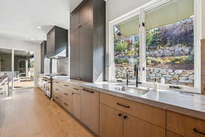 Kitchen featuring light wood-style floors, light stone counters, range with two ovens, backsplash, and modern cabinets
