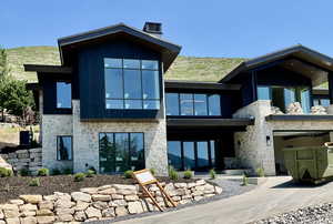 Rear view of house featuring stone siding and a garage