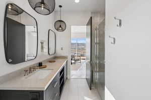 Bathroom featuring a shower stall, light tile patterned floors, double vanity, and recessed lighting