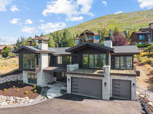 Contemporary home with a chimney, stone siding, driveway, and an attached garage