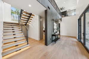 Staircase featuring plenty of natural light, wood finished floors, recessed lighting, and a high ceiling