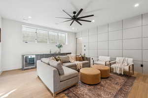 Living room featuring bar with sink, beverage cooler, recessed lighting, light wood-type flooring, and a ceiling fan