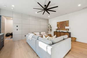 Living room featuring a ceiling fan, recessed lighting, and light wood finished floors
