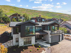 Contemporary house featuring stone siding, an attached garage, and driveway