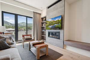 Living room with a fireplace, wood finished floors, and built in shelves