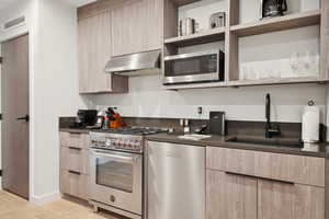 Kitchen with open shelves, light brown cabinets, stainless steel appliances, and modern cabinets