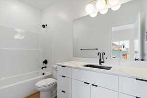 Bathroom with shower / washtub combination, vanity, and light wood-style floors