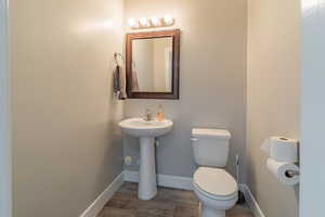 Half bath featuring baseboards and wood finished floors