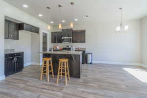 Kitchen featuring recessed lighting, light wood-style flooring, a chandelier, stainless steel appliances, and pendant lighting