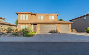View of front of property featuring concrete driveway, stone siding, a garage, and stucco siding