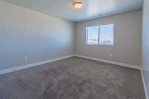 Empty room featuring carpet and baseboards