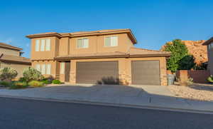 View of front facade with driveway, stone siding, stucco siding, and a garage