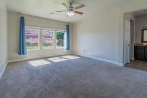 Carpeted spare room featuring a ceiling fan and baseboards