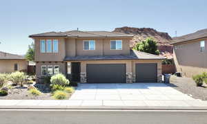 View of front of property featuring stucco siding, concrete driveway, an attached garage, and stone siding