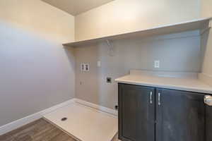 Laundry room featuring hookup for an electric dryer, washer hookup, wood finished floors, and cabinet space