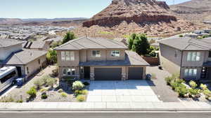 View of front of property with stucco siding, a residential view, concrete driveway, a mountain view, and stone siding